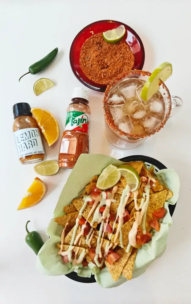 Michelada-olutdrinkki limelohkolla, Tajín-mausteella ja nachojen kanssa.