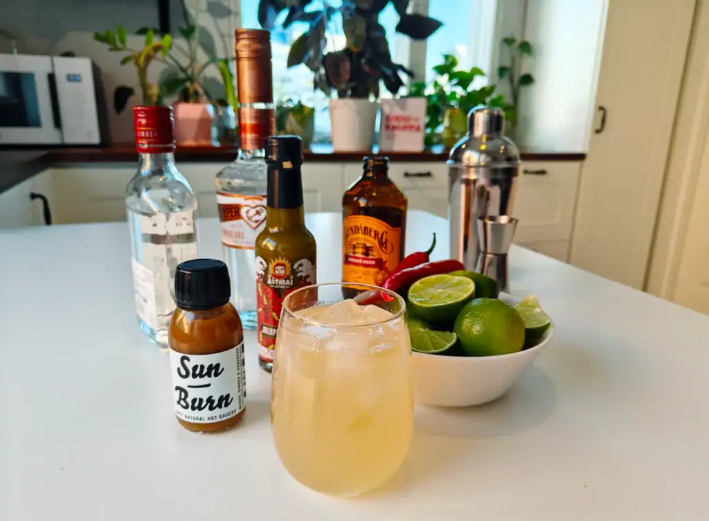 Moscow Mule -drinkki ja reseptiin tarvittavat aineksia, kuten limejä, inkivääriolutta ja chilikastikkeita.