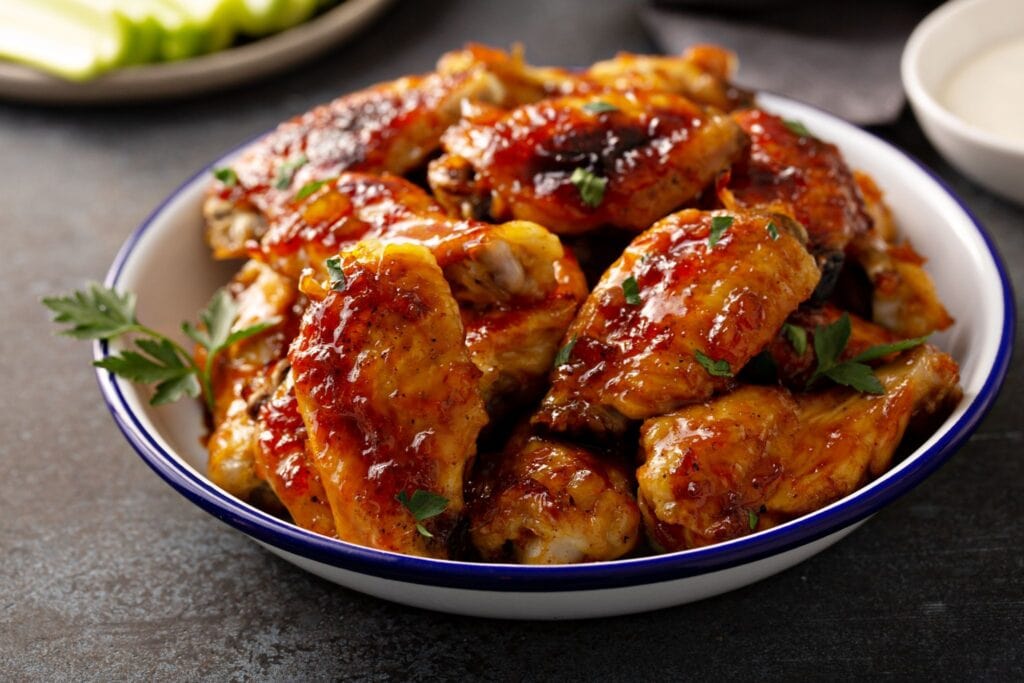 Chicken wings topped with wing sauce in a blue dish.