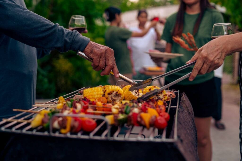Grilli täynnä kesän grilliherkkuja, kuten vartaita, maissia ja grillattuja kasviksia.